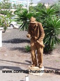 Een man geverfd in zandkleur die als standbeeld speelt.