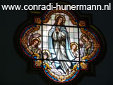 Een glas-in-loodraam met een biddende vrouw.